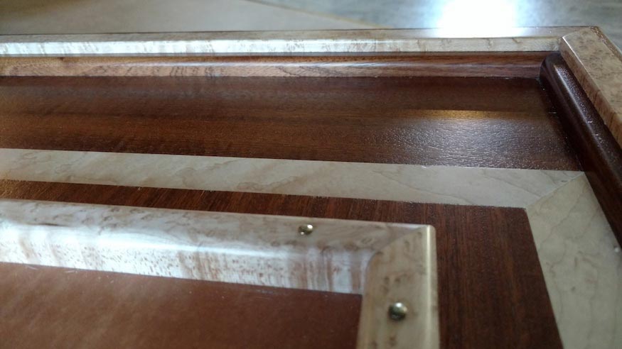 A detail of a corner of a cabinet made with Sapele inlays.