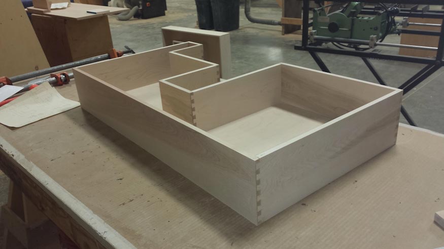 A finished drawer box with custom cutouts.