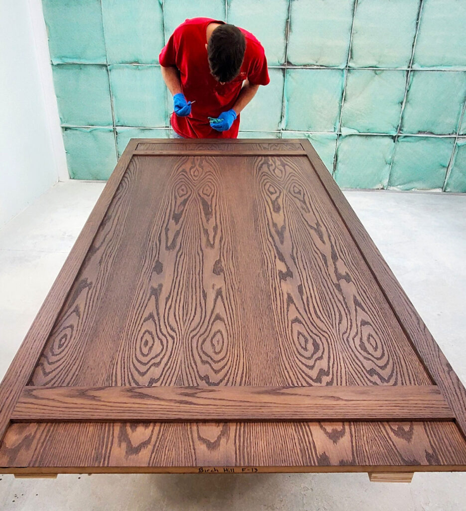 Dustin F. works on finishing a fixture that really shows of the rich color and wood grain. | Birch Hill Ski and Snowboarding Lodge | DP Juza Custom Woodworking