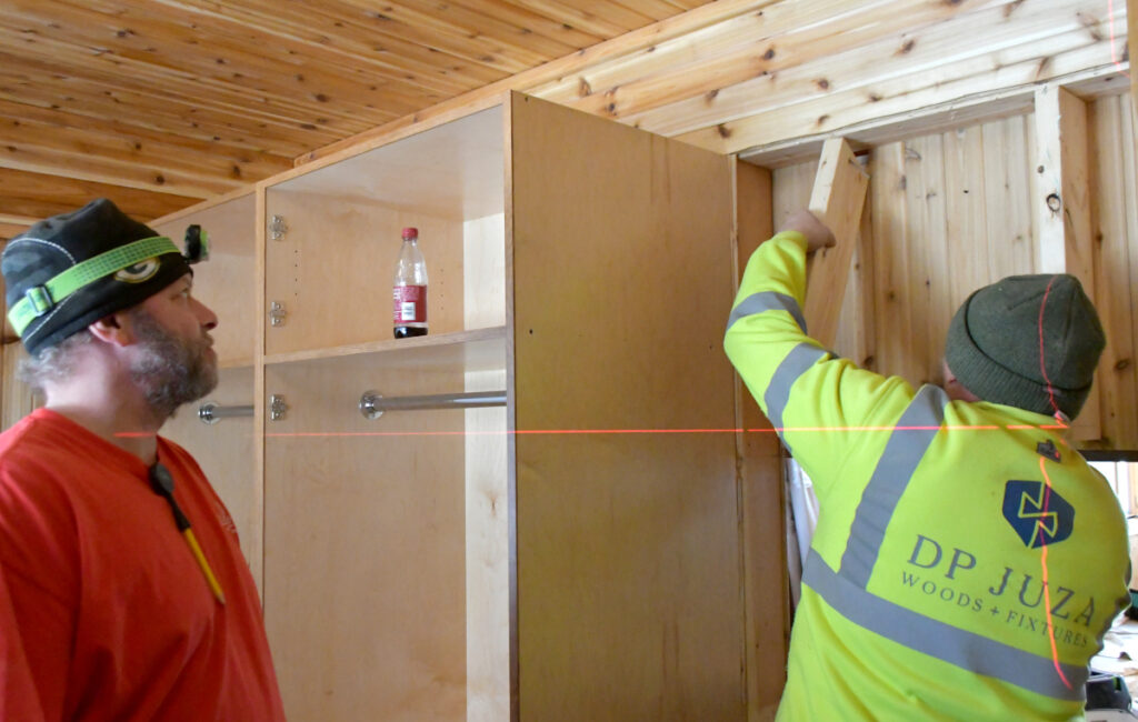 Two men work to install a closet in the entryway of a home.