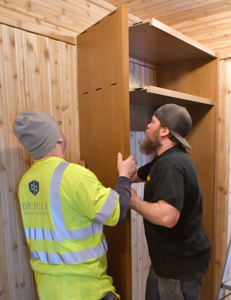 The side of a closet is installed by two men.